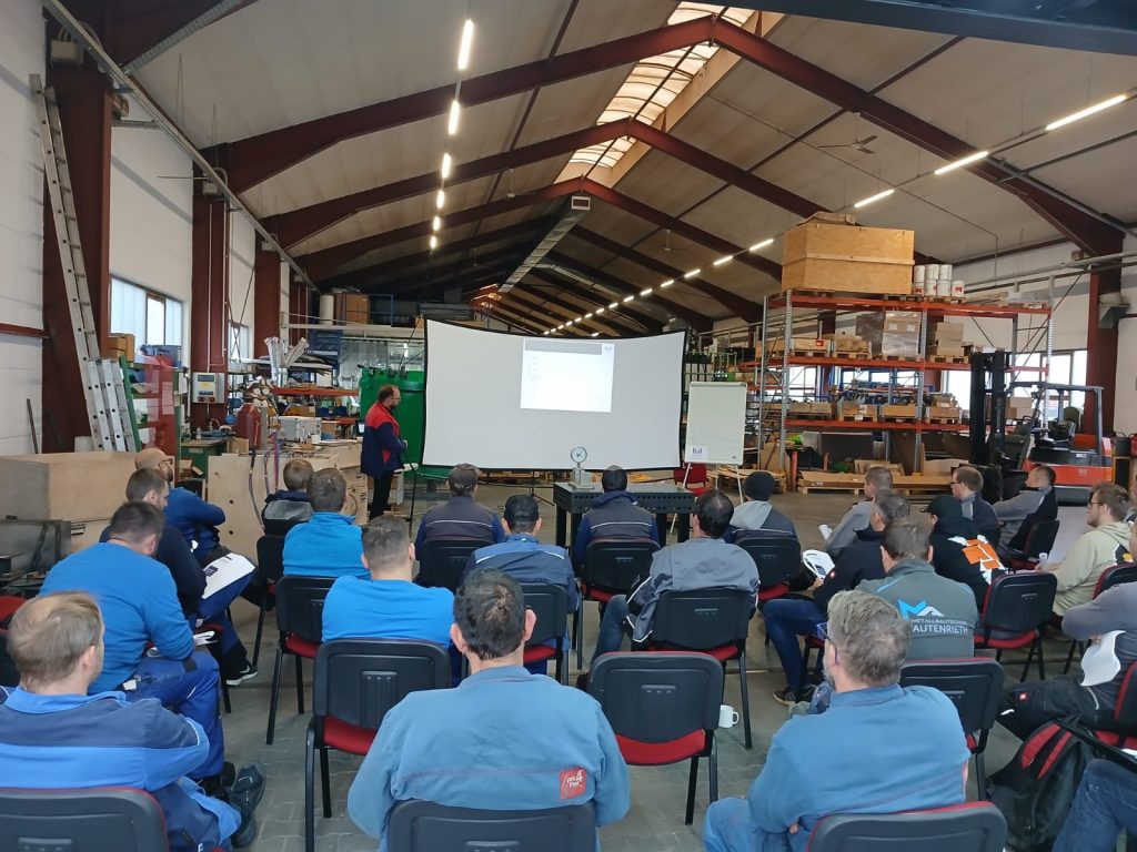 Teilnehmer bei einem Flammricht-Seminar in einer Werkstatt mit Präsentation